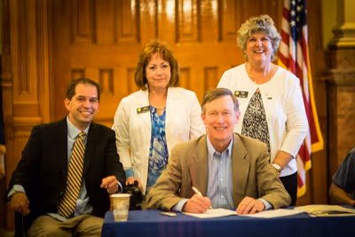 Chris at a bill signing ceremony with then Representative Dianne Primavera, Senator Nancy Todd, and then Governor Hickenlooper